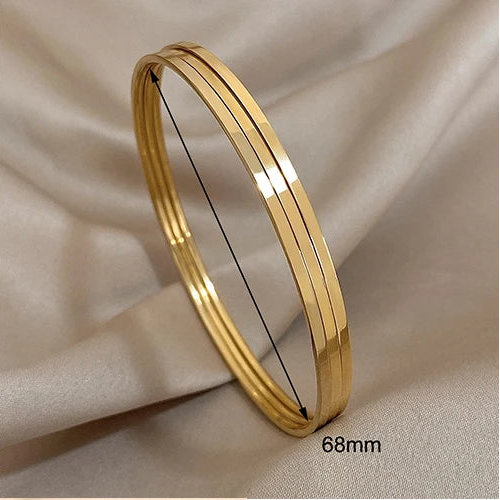 Gold bangles of different sizes on a neutral background