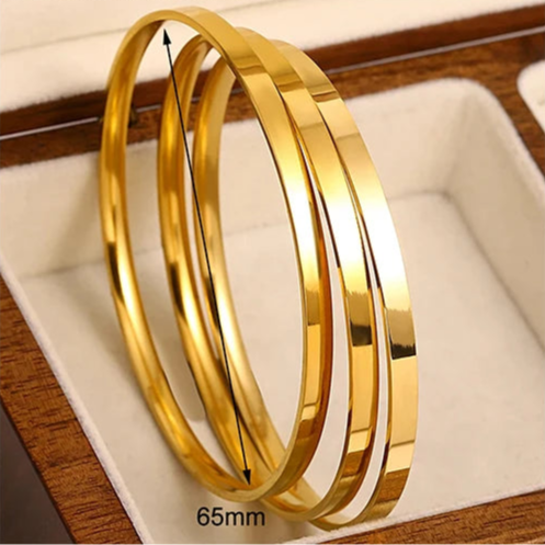 Gold bangles of different sizes on a neutral background