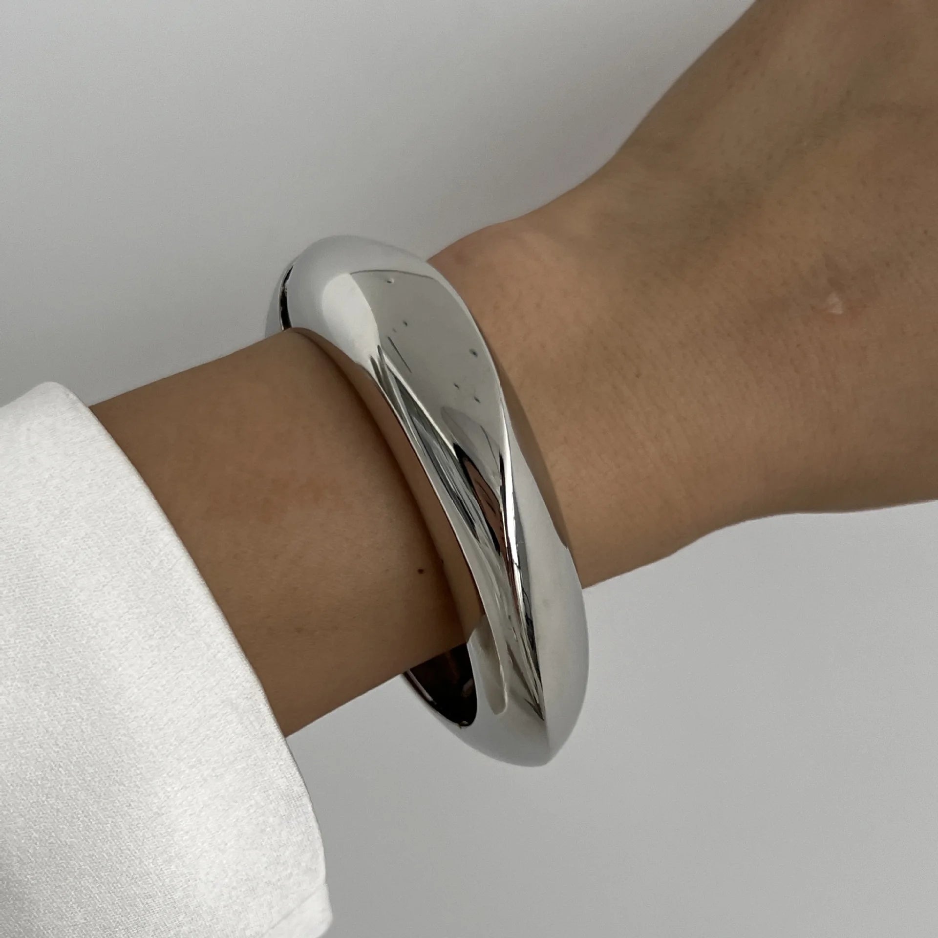 Silver bangle on a wrist against a neutral background