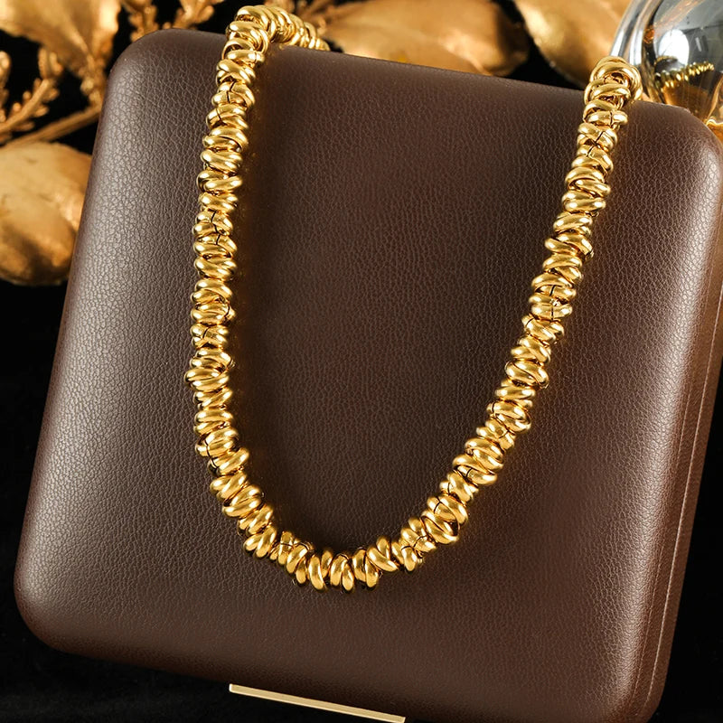 Gold necklace on a brown handbag with a blurred gold leaf background