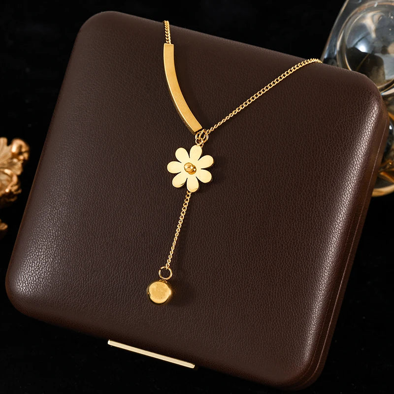 Gold necklace with a flower pendant on a brown surface