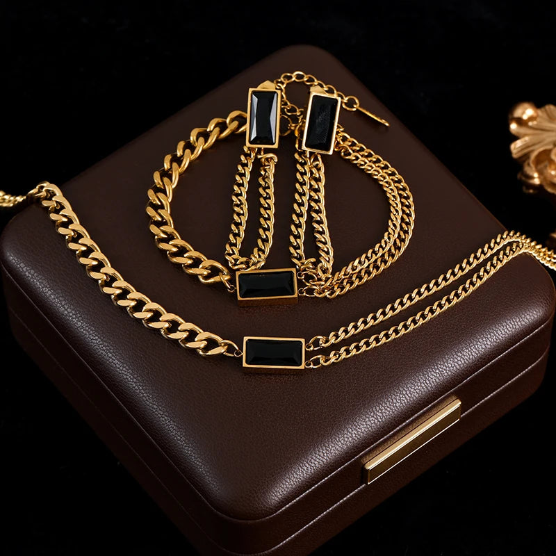 Gold chain necklace with black accents on a brown jewelry box