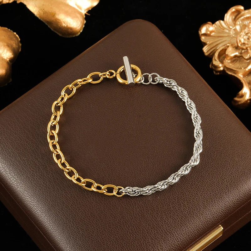 Two-tone gold and silver bracelet on a brown surface with decorative elements.