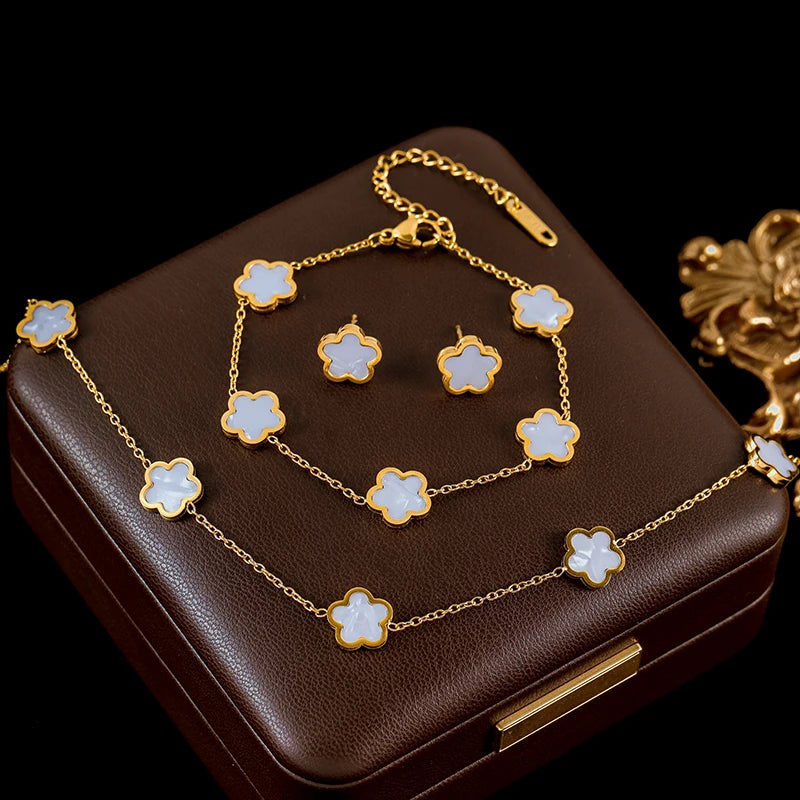 Jewelry set with gold chain and flower-shaped pendants on a brown jewelry box.