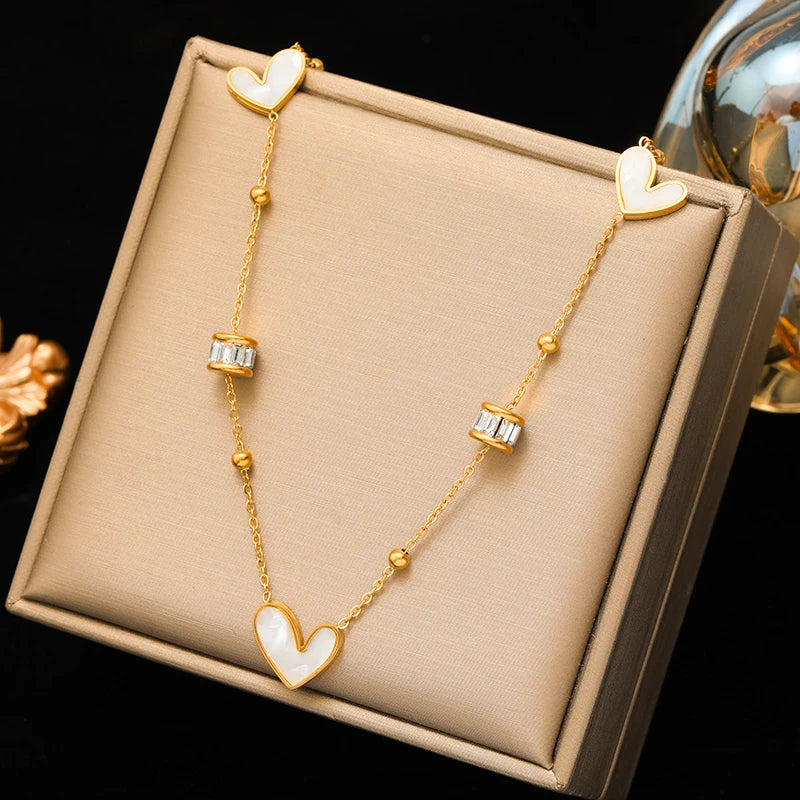 Gold necklace with heart-shaped pendants on a beige jewelry box