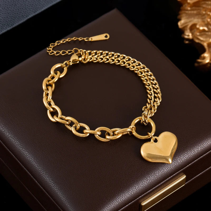 Gold chain bracelet with a heart charm on a dark surface