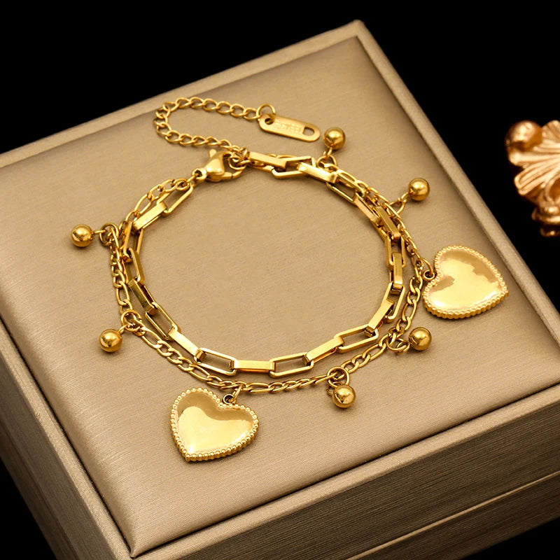 Gold bracelet with heart charms on a beige box