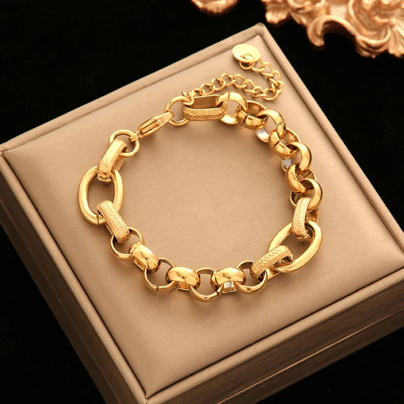 Gold chain bracelet on a beige jewelry box with a dark background