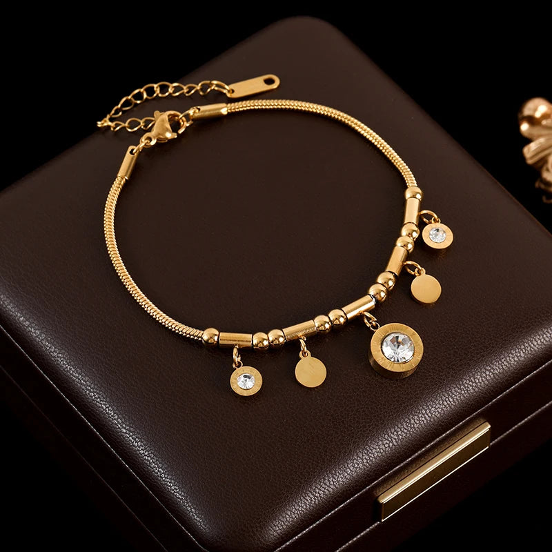 Gold bracelet with charms on a dark brown surface