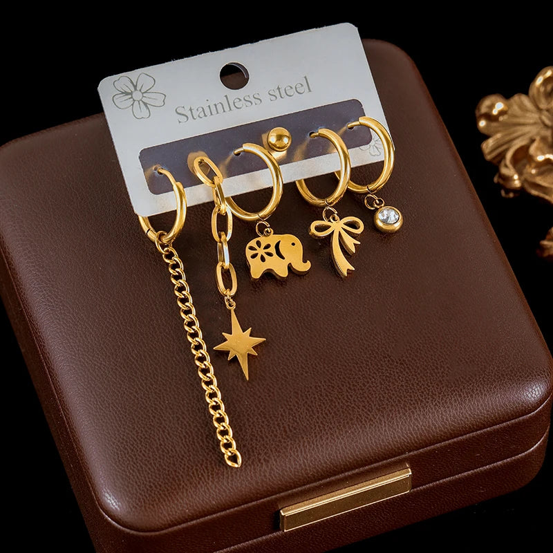 Set of gold earrings on a display card with a brown jewelry box background
