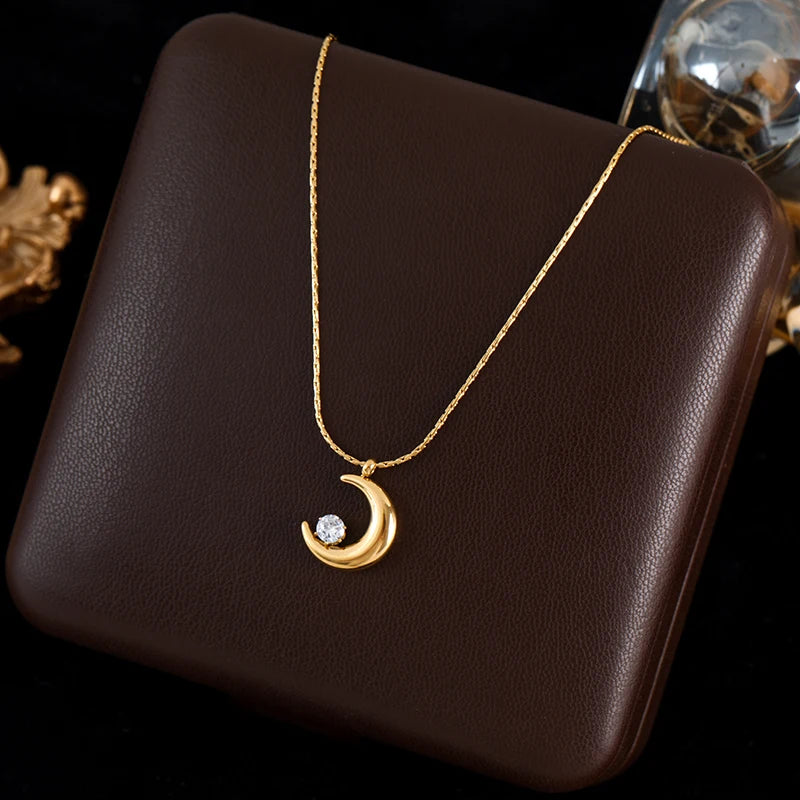 Gold necklace with a crescent moon pendant on a brown surface