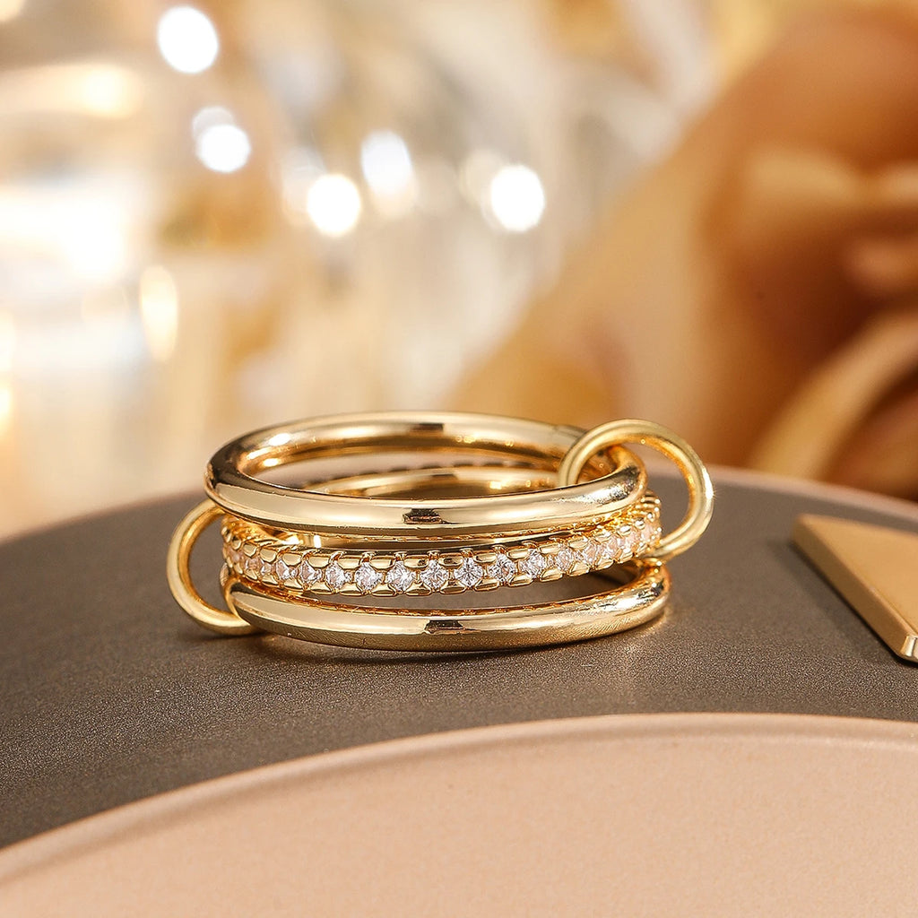 Three gold rings with diamond accents on a reflective surface with a blurred background
