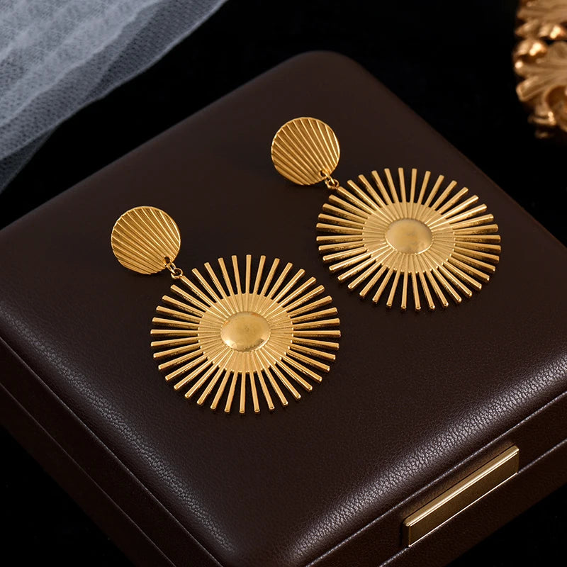 Gold sunburst earrings on a black jewelry box